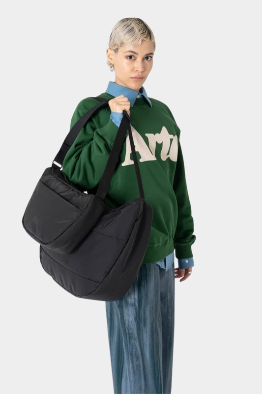 Bolso Ucon Acrobatics Adam Half-Moon Mini negro llevado al hombro, con silueta de media luna y correa regulable
