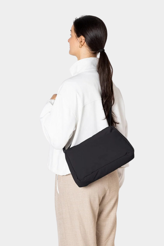 Bolso Ucon Acrobatics Emi Puffy negro llevado al hombro, con silueta acolchada y correa regulable para diario