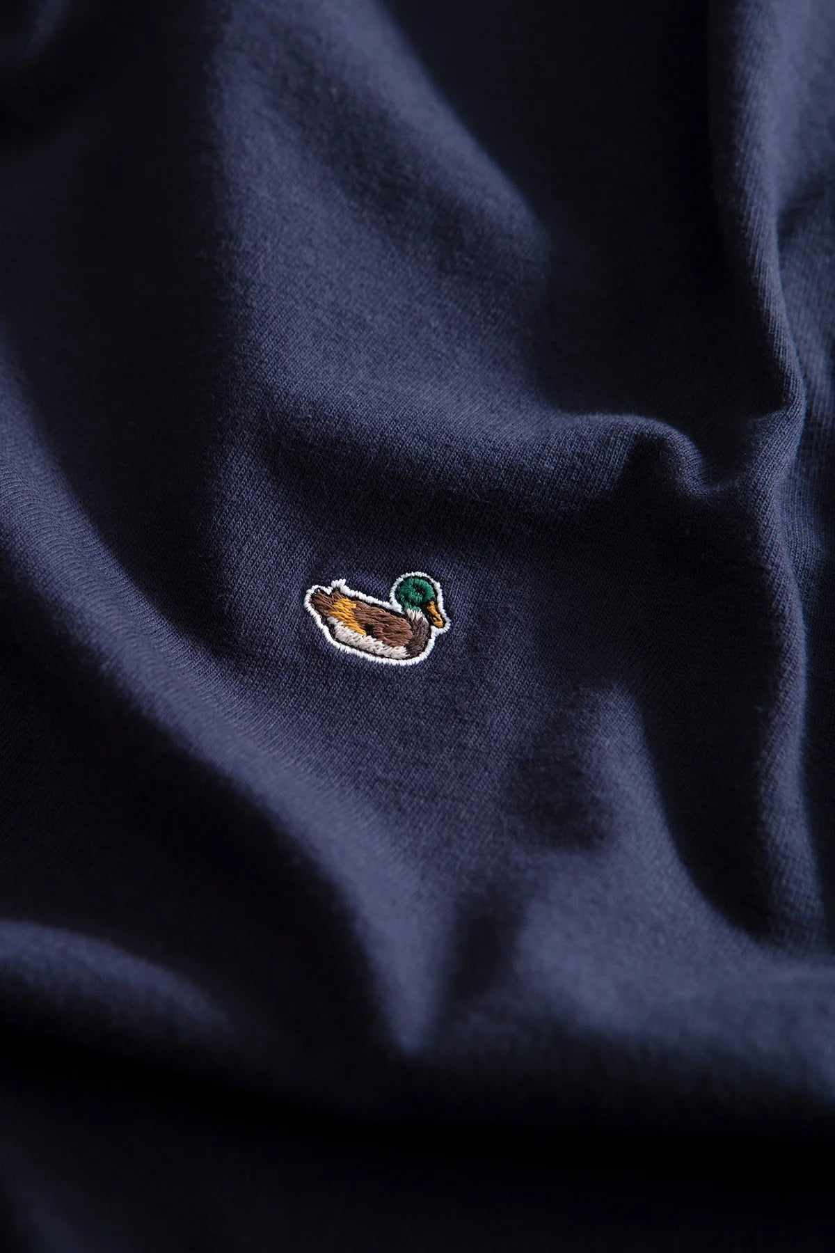 Detalle del icónico pato bordado en la camiseta azul marino Duck Patch de Edmmond Studios para hombre