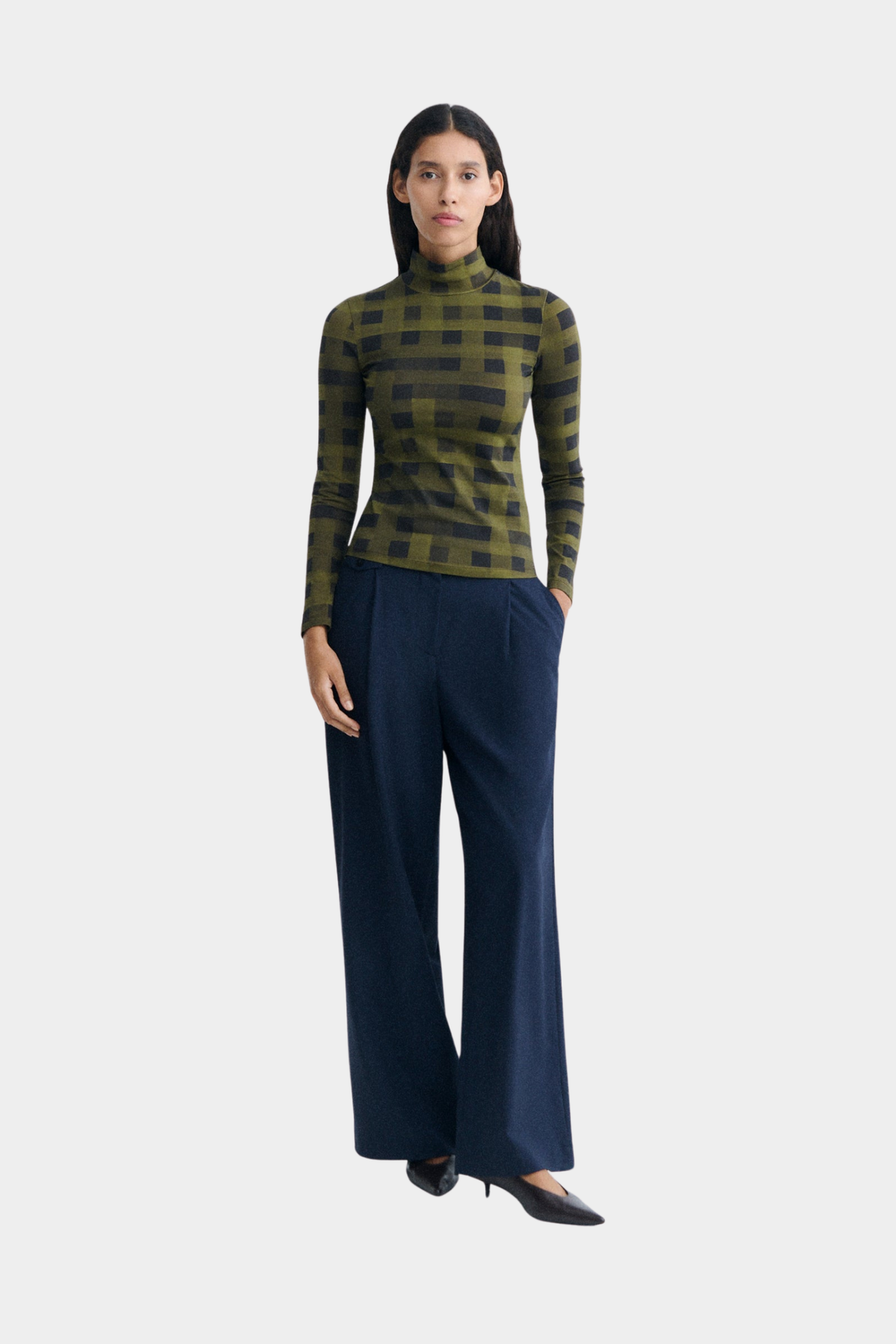 Top verde Ellen de Thinking Mu puesto, con manga larga, cuello alto y estampado geométrico de cuadros