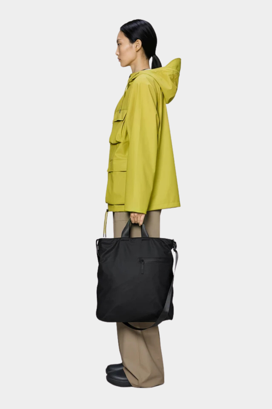 Bolso Rains Dash Tote Black en color negro llevado en la mano con diseño amplio e impermeable