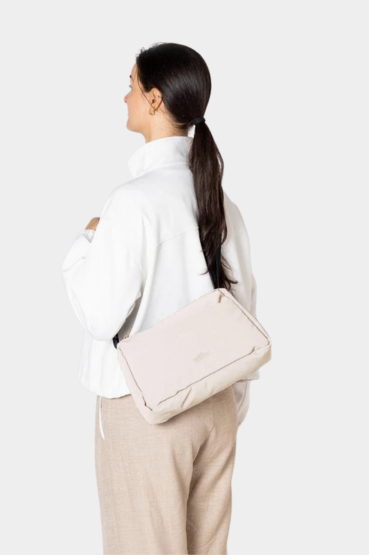 Bolso Ucon Acrobatics Emi Puffy Light Apricot llevado al hombro, con silueta acolchada en tono crema claro