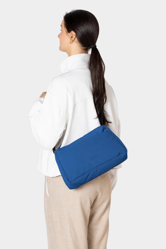 Bolso Ucon Emi Puffy Royal Blue llevado al hombro, con silueta acolchada y correa regulable en color azul