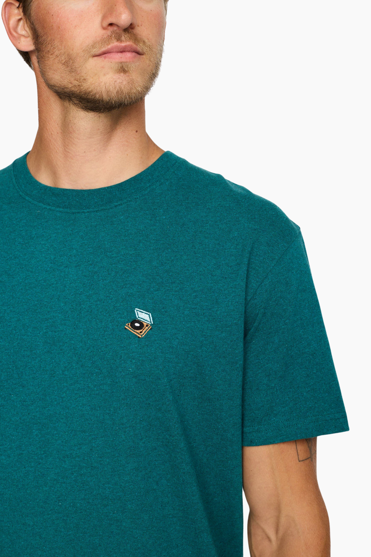 Detalle del pequeño bordado multicolor en el pecho de la camiseta Petrol 1449 PLA de Revolution para hombre