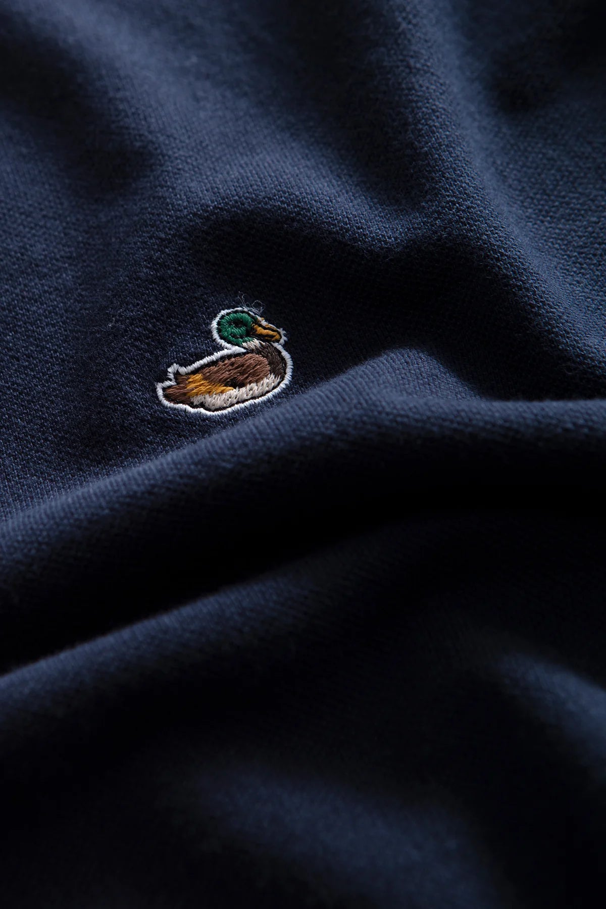 Detalle del icónico pato bordado en el Duck Polo azul marino Edmmond Studios de algodón orgánico