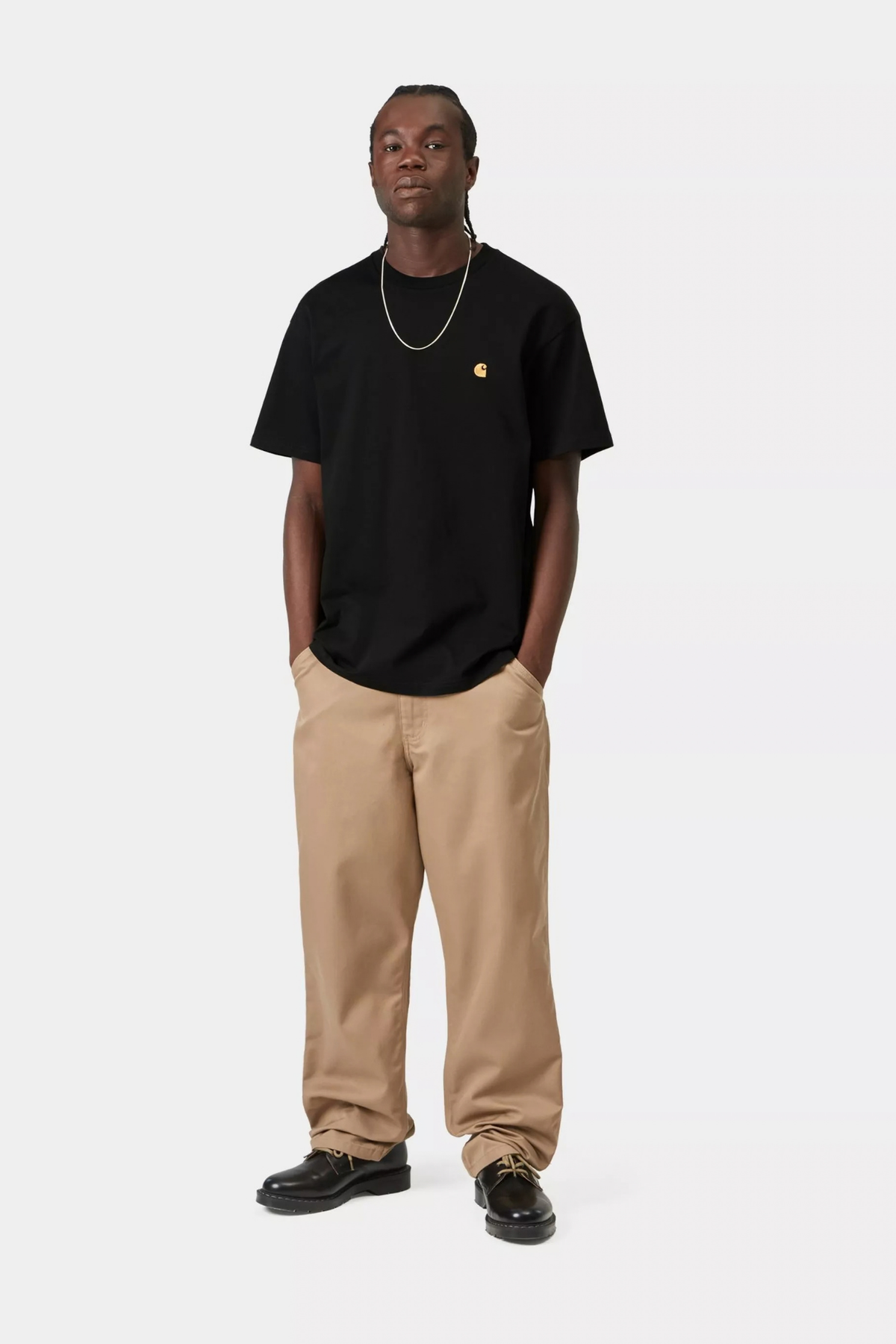 Look de hombre con camiseta Carhartt WIP S/S Chase Black, negra con logo dorado bordado en el pecho