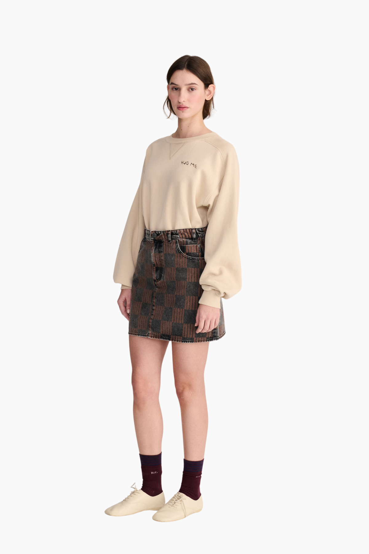 Look de mujer con sudadera beige Hug Me de Bobo Choses de corte holgado combinada con minifalda estampada