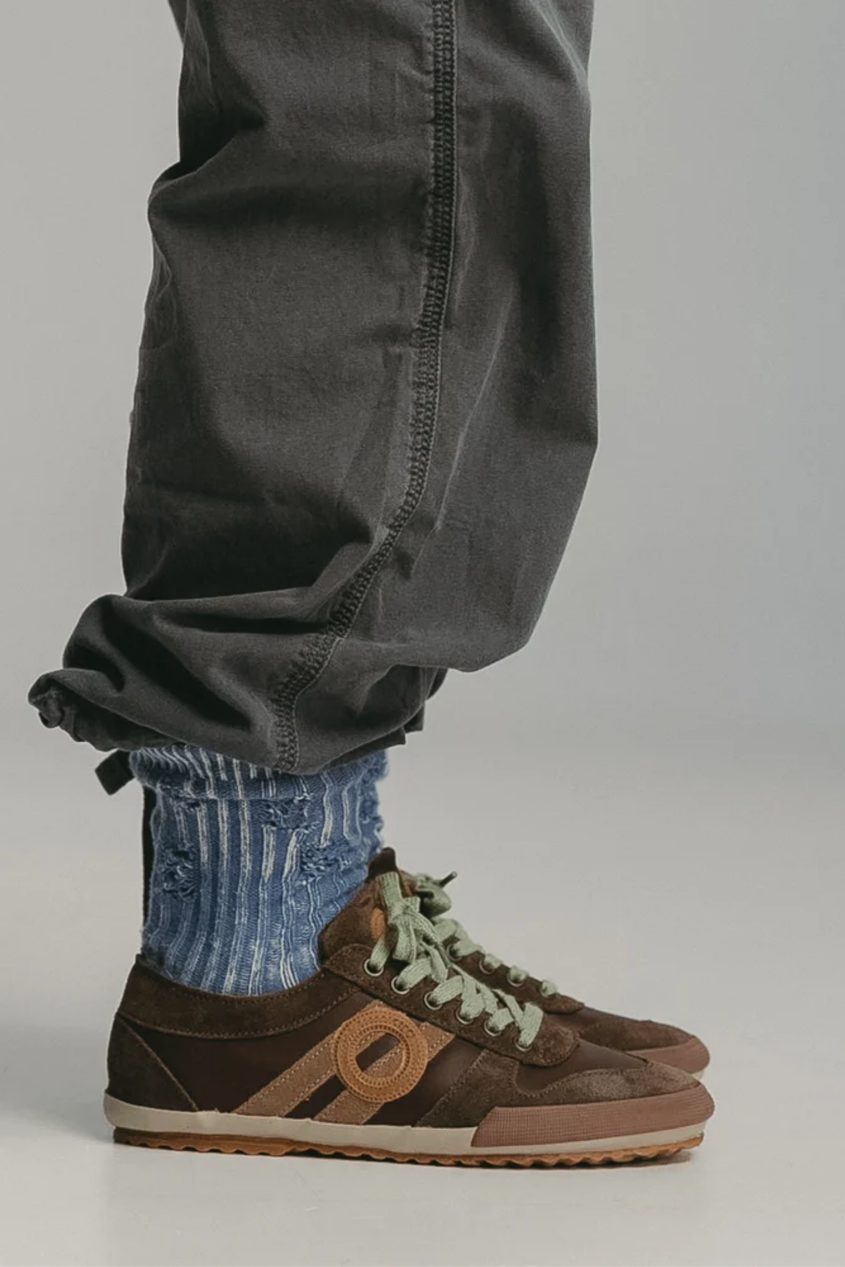 Zapatillas Aro Ido Wash Walnut de mujer puestas con pantalón oscuro, diseño marrón de inspiración retro
