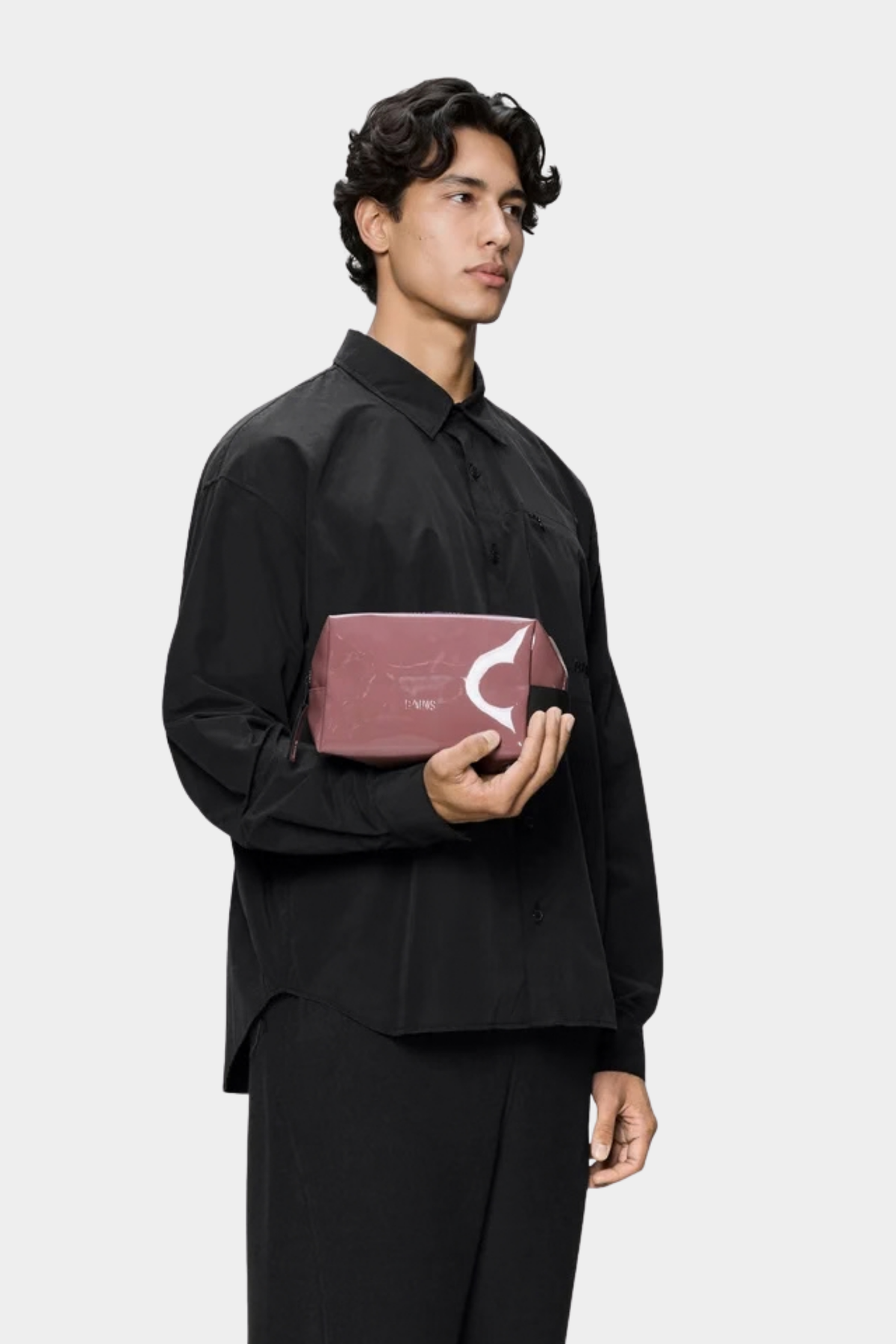 Neceser Rains Wash Bag Small Tempt sostenido en la mano, con formato compacto y asa lateral de transporte