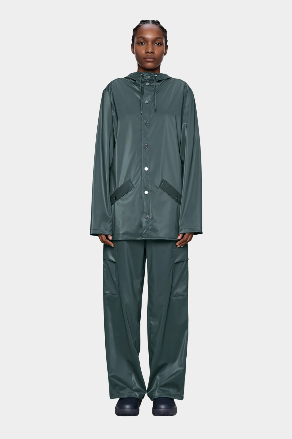 Rains Jacket Mystique unisex puesto, con tono verde azulado oscuro, capucha ajustable y corte regular